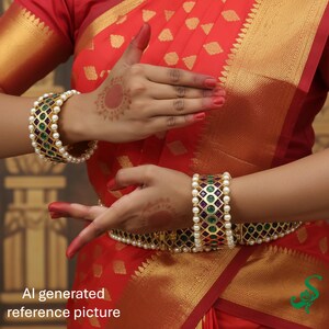 May include: Gold-toned bangles with green and purple gemstones and white pearls. The bangles are worn on a person's wrists, with a red and gold sari in the background. The image includes the text "AI generated reference picture".