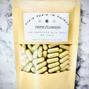 May include: A tan paper bag with a clear window displaying numerous light green capsules. The bag has a white label with the text "Liv's Tea's 'N Things" and "Hops Flowers". The label also states "120 Capsules with 350+ MG Each" and "Best if Used by June 2028".