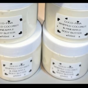 Puede incluir: Cuatro tarros blancos de Coco-Pina Whipped Coconut & Pineapple Body Butter, cada uno con una tapa blanca y una etiqueta con texto negro y detalles de corazón. Los tarros contienen un producto cremoso blanquecino, y cada tarro es de 150 ml.