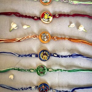 Puede incluir: Seis pulseras hechas a mano con dijes circulares que presentan ilustraciones de personajes de dibujos animados. Cada pulsera está elaborada con hilo trenzado en varios colores, incluyendo rosa, rojo, naranja, azul, verde y azul oscuro.