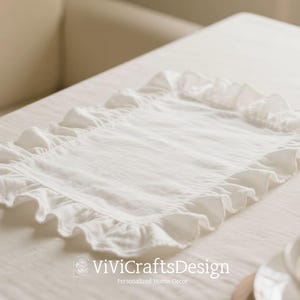 May include: White linen table runner with a ruffled edge. The runner is on a white tablecloth. The text "ViViCraftsDesign Personalised Home Decor" is visible in the bottom right corner of the image.