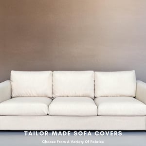 May include: A white three-seater sofa with a light beige fabric cover. The sofa has three cushions and a simple design. "TAILOR-MADE SOFA COVERS Choose From A Variety Of Fabrics" is written in black text below the sofa.