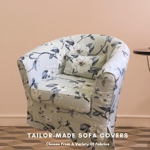 May include: A floral-patterned armchair with a matching pillow. The fabric features large white flowers with gray and blue accents on a light green background. The text "TAILOR-MADE SOFA COVERS" and "Choose From A Variety Of Fabrics" is visible.