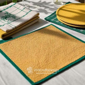 Könnte beinhalten: Zwei gelbe Tischsets mit grünem Rand. Die Tischsets sind aus strukturiertem Stoff und haben einen dezenten Glanz. Die Tischsets liegen auf einer weißen Tischdecke mit einer grün-weiß karierten Serviette und einer gelb-grün karierten Serviette.