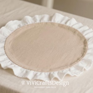 May include: A circular beige placemat with a white, ruffled border. The placemat is made of a soft fabric and is intended for home decoration. The image includes the text "ViViCraftsDesign Personalized Home Decor".