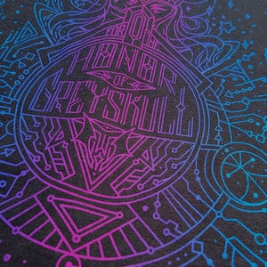 Puede incluir: Camiseta gris oscuro con un dise&ntilde;o geom&eacute;trico vibrante en azul y morado. El dise&ntilde;o presenta un emblema circular con el texto "FOR THE THRONE OF GREYSKULL" y un intrincado arte lineal.