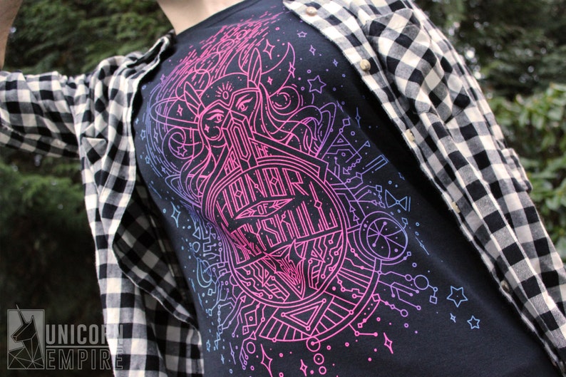 Puede incluir: Camiseta negra con un vibrante dise&ntilde;o gr&aacute;fico en rosa ne&oacute;n y azul. El dise&ntilde;o presenta un emblema circular con el texto "For the Honor of Skryll" y formas geom&eacute;tricas. Una camisa a cuadros en blanco y negro se usa encima.