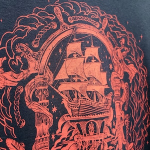 A closeup of the red pirate illustration shows the pirate ship, ropes, and the helm of the ship.