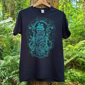 An illustration of the theme gentleman pirates is screen printed in teal blue ink on a black t-shirt. The illustrated typography on the bottom of the shirt reads fun with friends at sea.