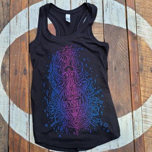 Puede incluir: Camiseta sin mangas negra con un vibrante dise&ntilde;o gr&aacute;fico azul y morado. El dise&ntilde;o presenta una ilustraci&oacute;n detallada con el texto "Hannah Greysull" en un patr&oacute;n circular. La camiseta sin mangas est&aacute; hecha de un material suave.