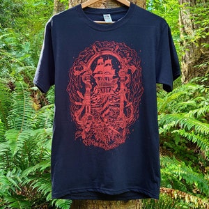 An illustration of the theme gentleman pirates is screen printed in bright red ink on a black t-shirt. The illustrated typography on the bottom of the shirt reads fun with friends at sea.