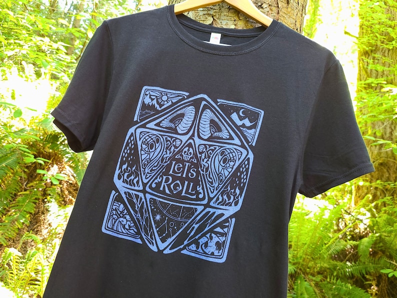 May include: Black t-shirt featuring a blue graphic of a stylised dice with the text "Let's Roll" on it.