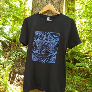 May include: Black t-shirt featuring a blue graphic of a stylised dice with the text "Let's Roll" on it.