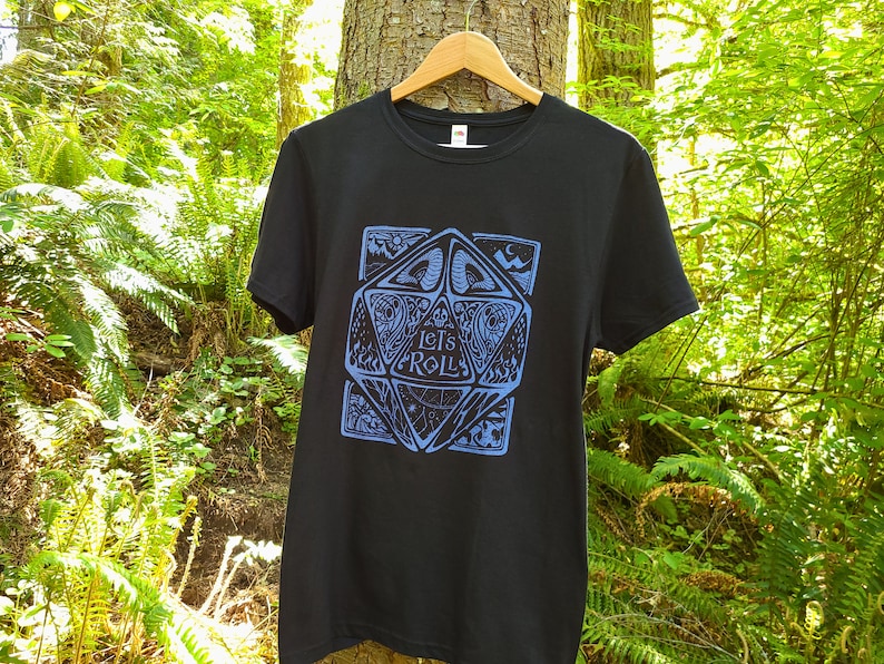 May include: Black t-shirt featuring a blue graphic of a stylised dice with the text "Let's Roll" on it.