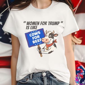 May include: White t-shirt with the text "WOMEN FOR TRUMP" IS LIKE" above a cartoon cow holding a sign that reads "COWS FOR BEEF". The cow has a red bandana and is holding a wooden sign with a blue border.