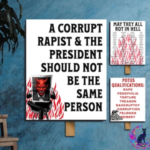 May include: Three white signs with text and illustrations. The largest sign reads "A CORRUPT RAPIST & THE PRESIDENT SHOULD NOT BE THE SAME PERSON." Another sign says "MAY THEY ALL ROT IN HELL." The third sign lists "POTUS QUALIFICATIONS."