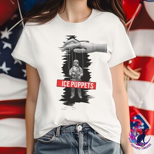 Puede incluir: Camiseta blanca con un gráfico en blanco y negro de una marioneta controlada por una mano. La marioneta es una persona con una máscara de gas. El texto "ICE PUPPETS" está en un rectángulo rojo.