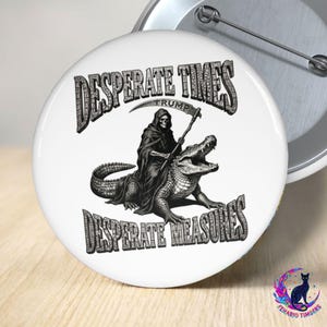 Könnte beinhalten: Weißer Button mit einer Schwarz-Weiß-Illustration. Das Bild zeigt eine Sensenmann-Figur, die ein Alligator reitet, mit dem Text "DESPERATE TIMES TRUMP DESPERATE MEASURES" in einer verwitterten Schrift.