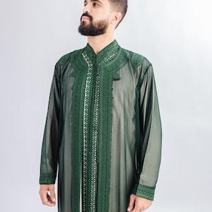 May include: A dark green, long-sleeved robe with intricate embroidery along the collar, front, and cuffs. The robe has a high collar and a flowing, semi-sheer fabric. The design features white and green decorative patterns.
