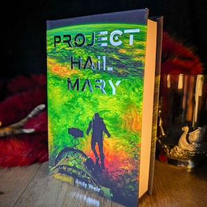 May include: A hardback book titled Project Hail Mary by Andy Weir. The cover features a vibrant green and orange swirling background with a silhouette of an astronaut standing on a spacecraft structure. The title is printed in reflective silver text.