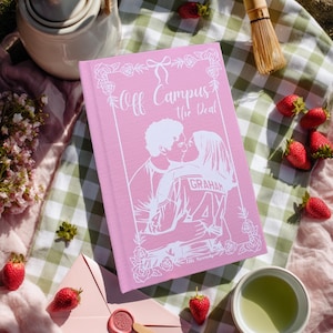 May include: A pink book titled "Off Campus The Deal" with a white illustration of a kissing couple. The scene includes strawberries, a teapot, a matcha whisk, and an envelope with a wax seal, suggesting a romantic picnic setting.