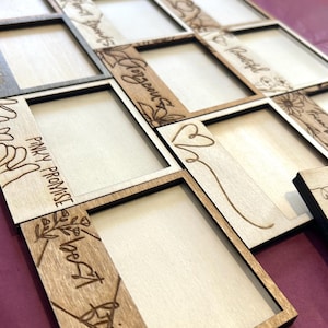Puede incluir: Marcos de fotos de madera con diseños y texto grabados con láser. Los marcos están dispuestos en un patrón de cuadrícula, con palabras como "Gorgeous" y "Best Friends" grabadas en los detalles de madera. Los marcos tienen un acabado de madera natural y están sobre un fondo morado.