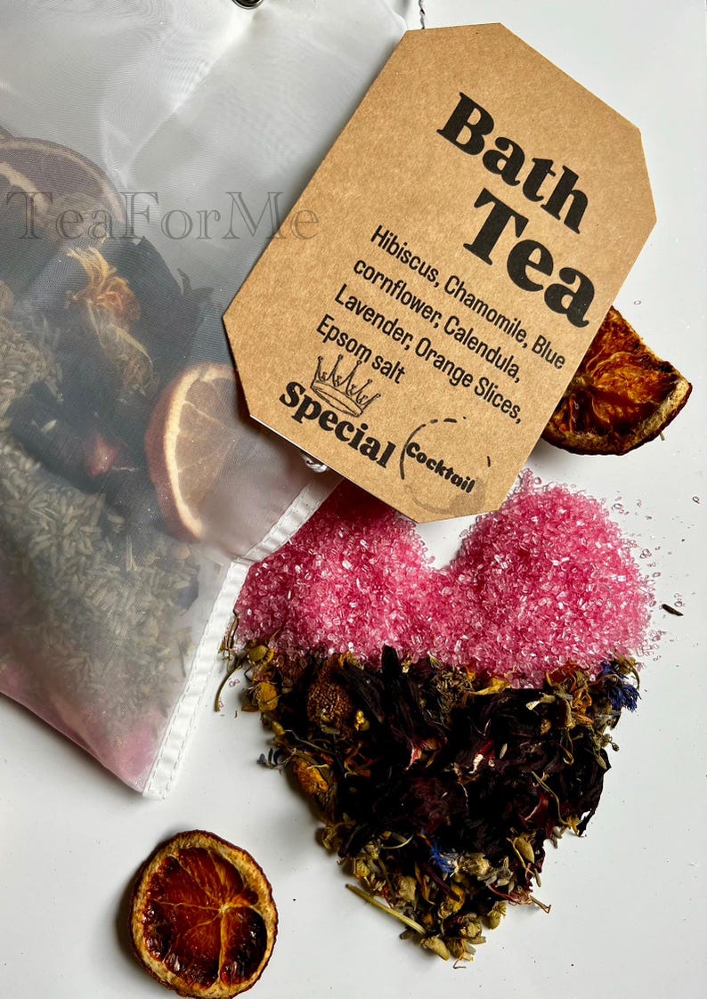 May include: A bath tea blend featuring a heart shape made of pink Epsom salt and dried flowers. A tag reads "Bath Tea" with ingredients listed. Includes orange slices and a tea bag.