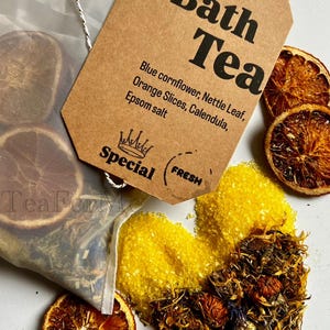 May include: Image of bath tea ingredients, including dried orange slices, blue cornflower, and Epsom salt. A brown tag reads "Bath Tea" with a list of ingredients. A small bag of tea is visible.