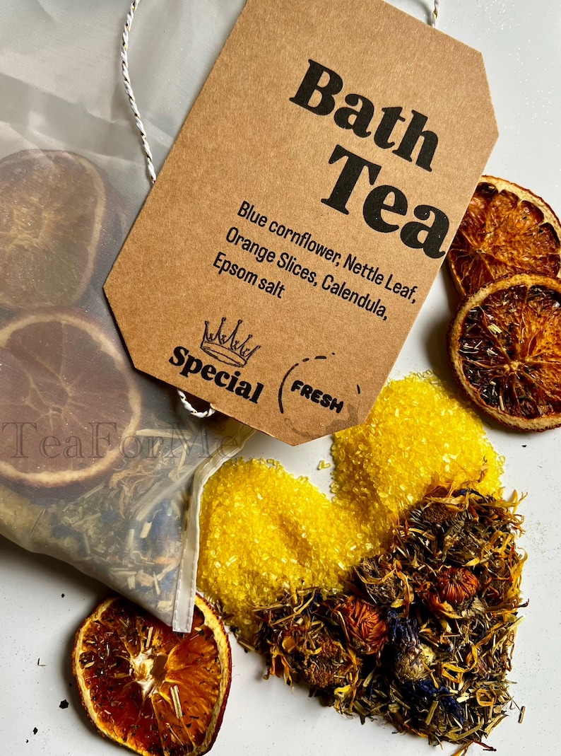 May include: Image of bath tea ingredients, including dried orange slices, blue cornflower, and Epsom salt. A brown tag reads "Bath Tea" with a list of ingredients. A small bag of tea is visible.