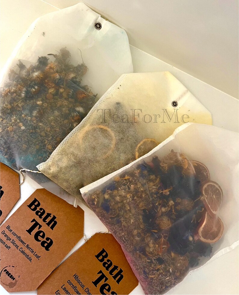 May include: Image of bath tea bags filled with dried herbs and flowers. The bags are in various shapes and sizes, some with tags that read "Bath Tea." Ingredients include blue cornflower, orange slices, and lavender. The text "Tea ForMe" is visible.