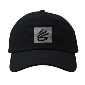 May include: A black baseball cap with a white square patch featuring a black stylized logo.