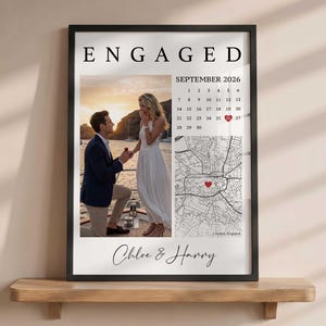 Puede incluir: Un póster vertical enmarcado titulado ENGAGED que muestra una fotografía de una pareja en un barco, un calendario de septiembre de 2026 con un corazón rojo en el día 26, un mapa en blanco y negro de Londres con un corazón rojo y los nombres Chloe & Harry.