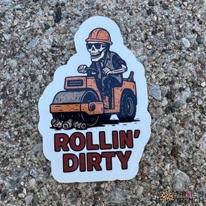 Puede incluir: Una pegatina que representa un esqueleto conduciendo un rodillo de vapor naranja, con casco y gafas de sol. La pegatina tiene las palabras "ROLLIN' DIRTY" en letras marrones. La pegatina está sobre un fondo blanco.