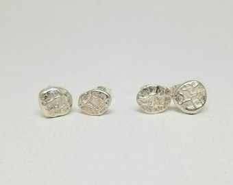 Könnte beinhalten: Ein Set mit drei silbernen Ohrsteckern mit einem strukturierten, organischen Design. Die Ohrringe sind klein und zart und wären ein tolles Geschenk für jemanden, der minimalistischen Schmuck liebt.