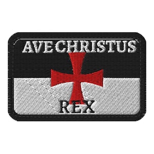 Op de afbeelding: Een rechthoekige geborduurde patch met een horizontaal verdeeld ontwerp met een zwarte bovenhelft en een witte onderhelft. Een rood kruis is in het midden geplaatst. De witte tekst AVE CHRISTUS staat bovenaan en het woord REX onderaan.