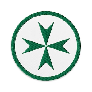 Puede incluir: Parche bordado redondo con una cruz de Malta verde sobre fondo blanco. La cruz está centrada dentro de un círculo blanco, bordeado por un ribete verde. El parche tiene un aspecto texturizado.