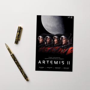 May include: A black and gold pen with a floral design next to a poster featuring four astronauts in helmets against a backdrop of the moon. The poster reads "Artemis II" and lists the mission details.