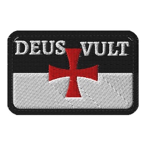 Puede incluir: Un parche rectangular bordado que presenta un diseño dividido horizontalmente con una mitad superior negra y una mitad inferior blanca. Una cruz roja está centrada sobre la división. El texto blanco DEUS VULT está bordado en la parte negra.
