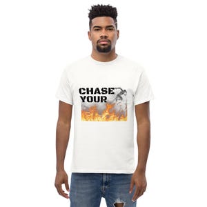 Op de afbeelding: Wit T-shirt met een zwarte grafische print die "CHASE YOUR" zegt met een zwart-witte afbeelding van een persoon die door vlammen rent.