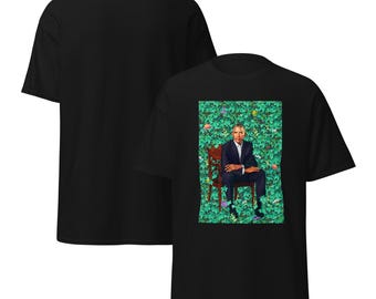 May include: Black t-shirt featuring a portrait of a person in a suit seated in a chair against a backdrop of green foliage and flowers. The back of the shirt is plain black.