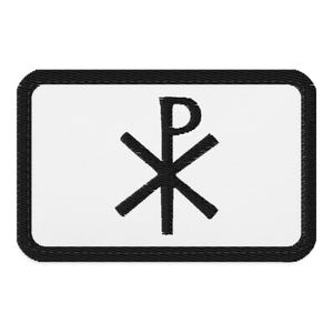 Può includere: Una toppa rettangolare ricamata con sfondo bianco e un bordo nero spesso. Al centro della toppa si trova un simbolo Chi Rho nero, composto dalle lettere greche Chi e Rho sovrapposte per formare un emblema religioso distintivo.