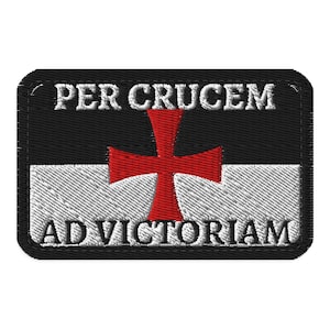 Op de afbeelding: Een rechthoekige geborduurde patch met een zwarte bovenhelft en een witte onderhelft. Een rood kruis is in het midden van de patch geplaatst. De tekst PER CRUCEM is in het wit bovenaan geborduurd en de tekst AD VICTORIAM in het zwart onderaan.