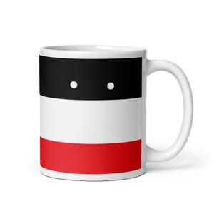 Puede incluir: Taza de cerámica blanca con un diseño que presenta una banda negra con dos puntos blancos, una banda blanca y una banda roja. La taza tiene un asa curva y un acabado brillante.
