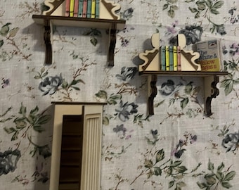 May include: Miniature wooden shelves and cabinet. Two shelves hold colorful books, and one shelf has a small book titled "The White & Yellow Pages". The cabinet has an open door. The items are set against a floral patterned background.