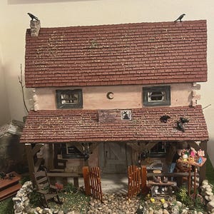 May include: A detailed miniature apothecary shop with a red tile roof, a wooden porch, and a stone pathway. The shop features a sign that reads "Apothecary" and is decorated with small crows. The shop has a rustic, handcrafted appearance.