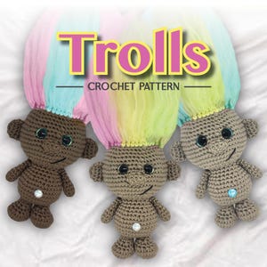 Peut inclure: Trois poupées trolls en crochet avec des cheveux en laine arc-en-ciel. Les poupées sont brunes avec des yeux noirs et un visage souriant. Les poupées sont assises sur une surface blanche. Le texte "Trolls Crochet Pattern" est au-dessus des poupées.