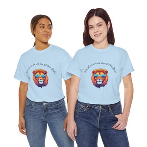 Könnte beinhalten: Zwei hellblaue T-Shirts mit einem Löwen-Motiv mit Sonnenbrille und dem Text "Keiner ist wie du und das ist deine Stärke!" in Schreibschrift. Die Models tragen blaue Jeans.