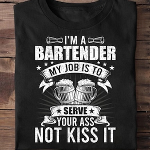 Pode incluir: Camiseta preta com um gráfico branco que diz "I'M A BARTENDER MY JOB IS TO SERVE YOUR ASS NOT KISS IT". O design inclui imagens de canecas de cerveja e coqueteleiras.