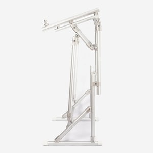 May include: A silver-colored adjustable laptop stand constructed from lightweight metal tubing. The frame features multiple hinged joints and support bars, allowing for height and angle modifications. It has a flat base and a top platform.