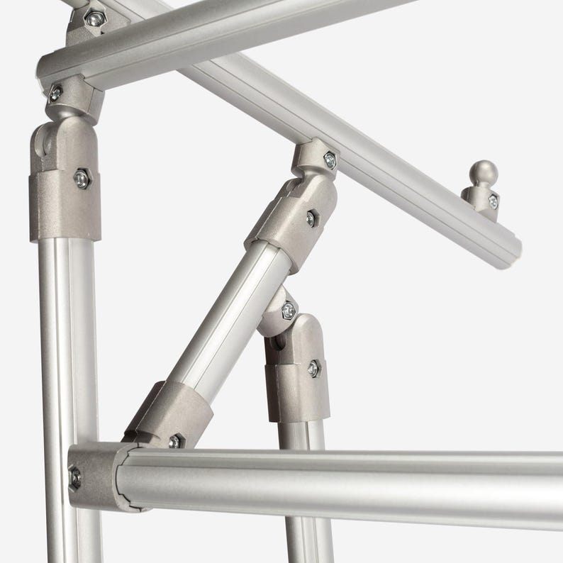 May include: A modular silver aluminum frame structure featuring cylindrical tubes connected by adjustable metal joints and fasteners. The assembly includes multiple intersecting bars and a small spherical attachment point on one of the top rails.